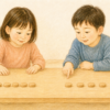 同じ数の木製チップを異なる間隔で並べ、見比べながら考える幼児2人のクレヨン画